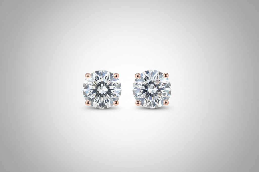 Diamond stud earrings held between fingers against a neutral background