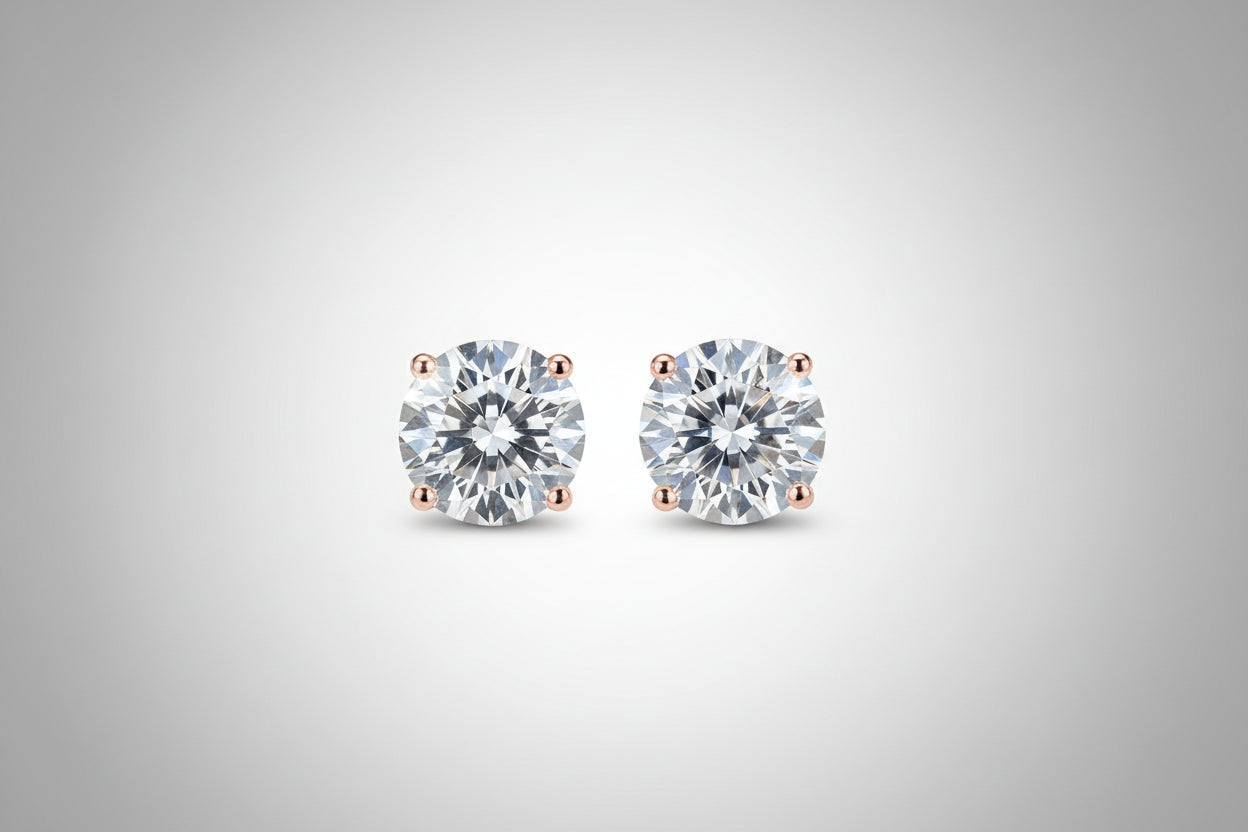 Diamond stud earrings held between fingers against a neutral background